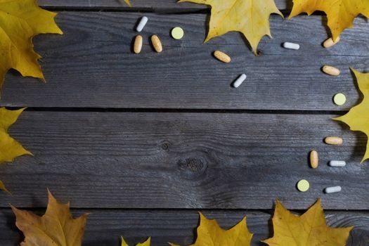 .Autumn foliage and medicines on wooden background.