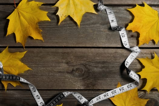 Autumn fallen leaves and measuring tape on wooden background