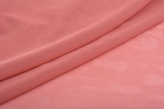 red Knitted elastic fabric, weaving of threads texture, crumpled fold. For underwear, sports clothes and swimwear. Space for text.