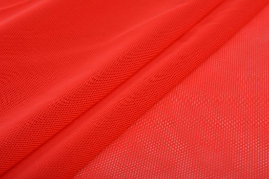 red Knitted elastic fabric, weaving of threads texture, crumpled fold. For underwear, sports clothes and swimwear. Space for text.