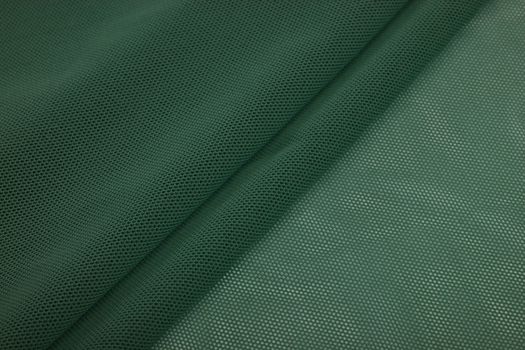 green Knitted elastic fabric, weaving of threads texture, crumpled fold. For underwear, sports clothes and swimwear. Space for text.