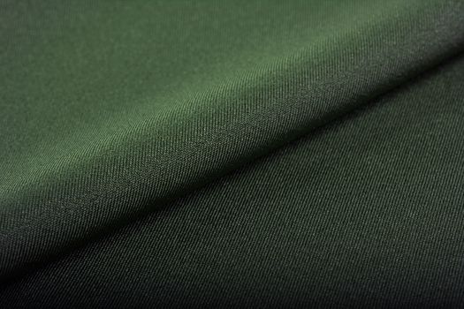 green Knitted elastic fabric, weaving of threads texture, crumpled fold. For underwear, sports clothes and swimwear. Space for text.