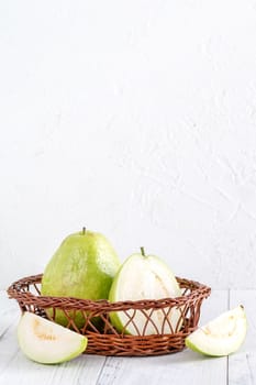 Delicious beautiful guava set with fresh leaves isolated on bright white wooden table background, close up.