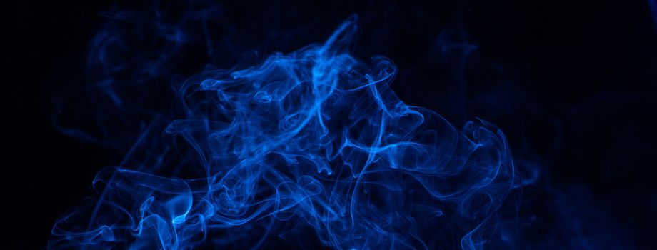 Conceptual image of blue color smoke isolated on dark black background, Halloween concept design element.