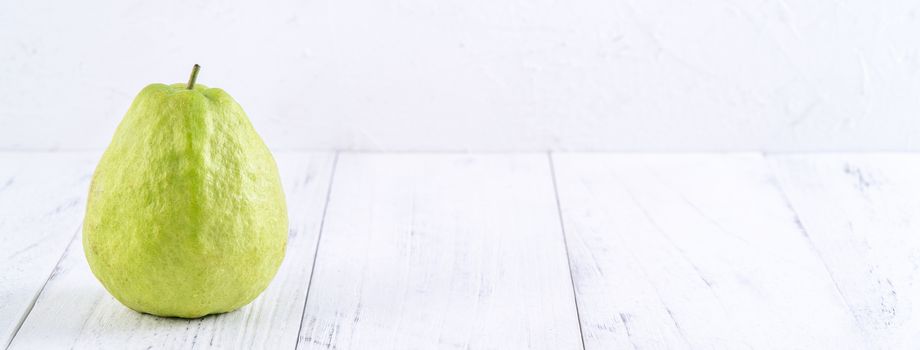 Delicious beautiful guava set with fresh leaves isolated on bright white wooden table background, close up.