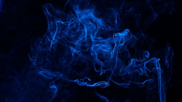 Conceptual image of blue color smoke isolated on dark black background, Halloween concept design element.