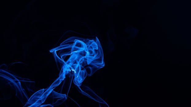 Conceptual image of blue color smoke isolated on dark black background, Halloween concept design element.