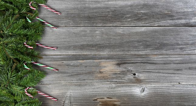 Merry Christmas and Happy New Year holiday concept with candy cane decorations on left side of weathered wooden boards