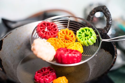 shot of colorful Fryums being shaken to remove excess oil from this popular north indian snack and street food. This sago and potato starch delicacy is a popular snack that is unhealthy but very tasty