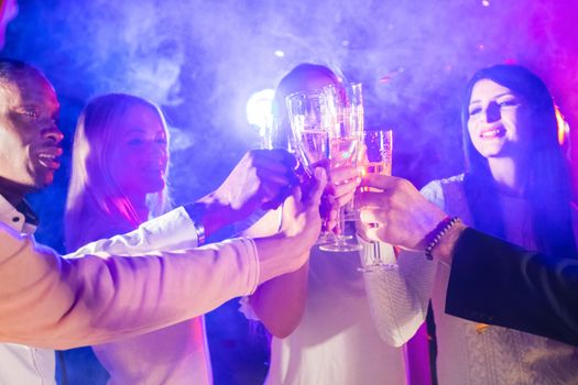 New year celebration party, holidays, nightlife and people concept - smiling friends clink glasses of champagne in night club