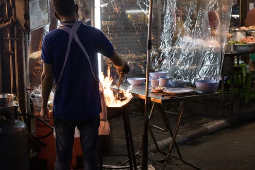 Chef is stirring cooking in wok at street food 