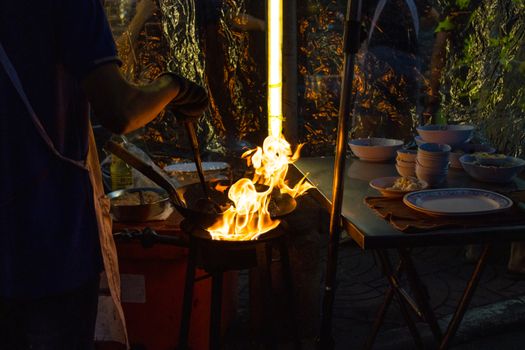 Chef is stirring cooking in wok at street food 