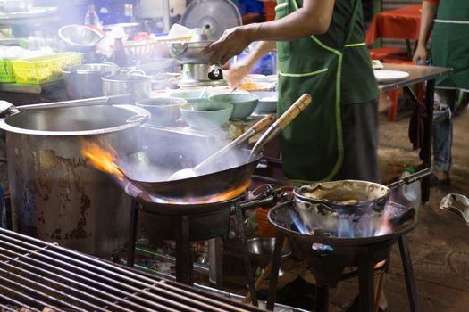 Chef is stirring cooking in wok at street food 