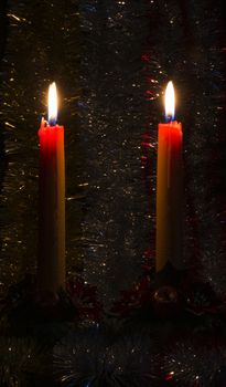 Christmas and New Year mood create two burning candles and bright tinsel