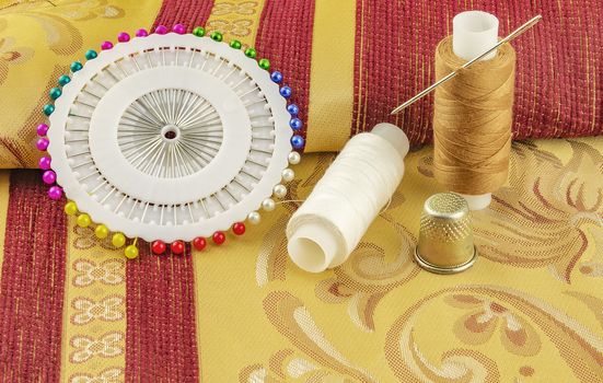 At curtain fabrics are two reels of thread for sewing with needle and thimble