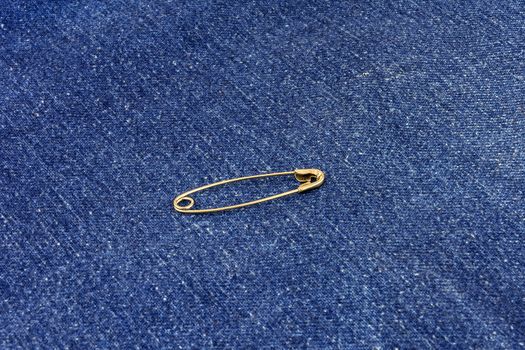 Metal buttoned pin lies on blue jeans material