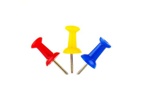 Three colored drawing pins inserted in the light background