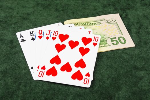 On the green baize is banknotes and poker hand of five cards