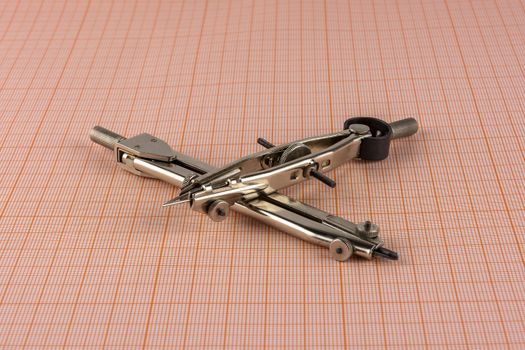 Two metal compass lying on a sheet of graph paper