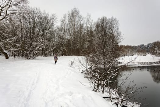 Lonely woman is walking on the bank of winter river