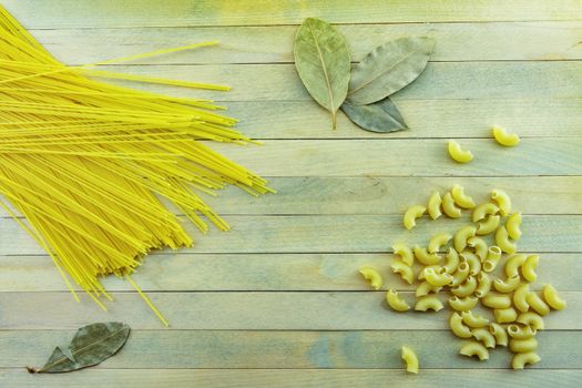 On a wooden surface lie pasta and bay leaf