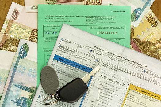 Documents of international car insurance with the ignition key and banknotes