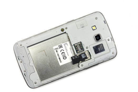 Smartphone with open rear lid lies on a light surface