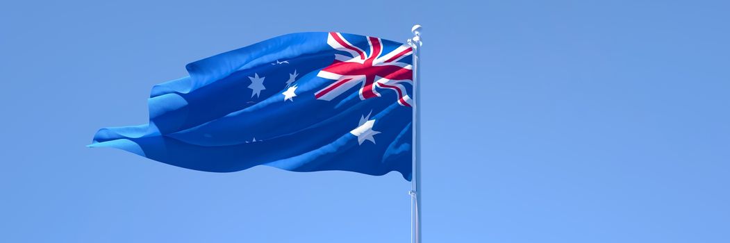 3D rendering of the national flag of Australia waving in the wind against a blue sky