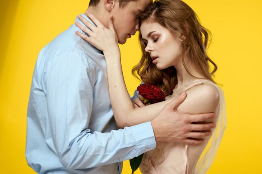 Enamored man and woman with red rose on yellow background cropped view close-up romance. High quality photo