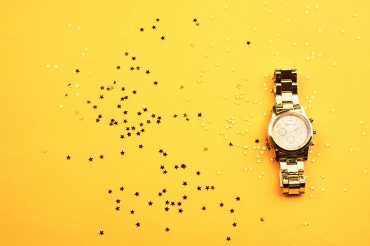 Wristwatch on yellow background and Copy Space glitter. High quality photo