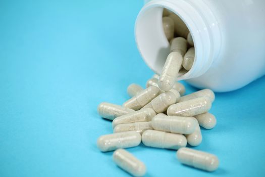 White bottle of capsules on blue background