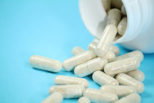 White bottle of capsules on blue background