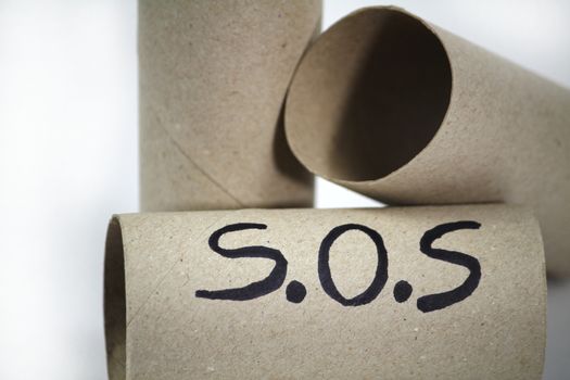 Three Empty toilet paper roll on white background with the word sos written on it