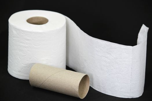 White toilet paper roll on black background next to empty one