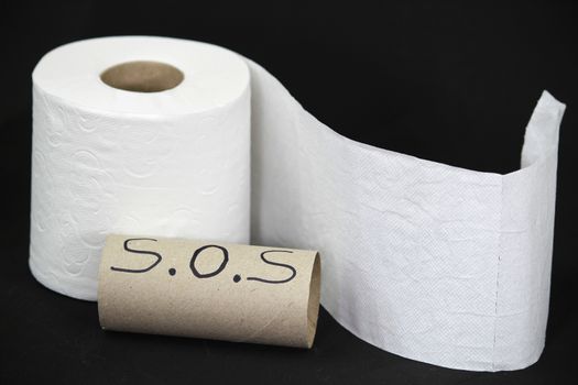 White toilet paper roll on black background next to empty one with the word sos written on il