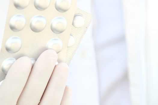 Male hand in white surgical glove holding pill blisters