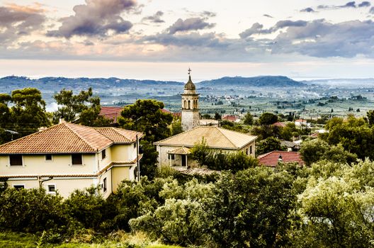 panoramic view of a sunset on the island of zakynthos with old bell tower of an orthodox church and in the background on the horizon you can see the Ionian sea