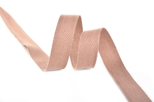 beige Twisted ribbon of cotton Keeper braid on white background. Tape For sewing clothes.