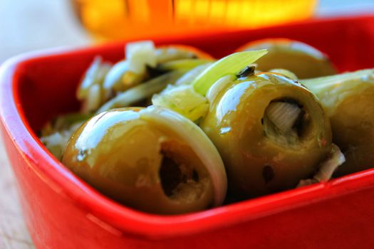 Delicious Spanish tapa. Olives with onion, oregano and olive oil served in red bowl