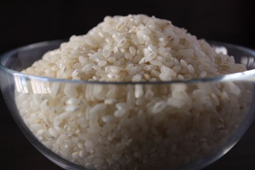 White rice texture and background in glass bowl. Grey background.