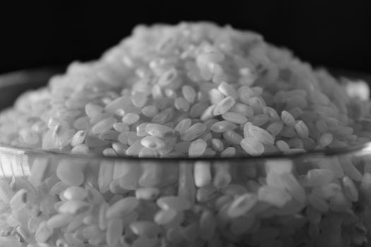 White rice texture and background in glass bowl. Grey background. Monochrome picture