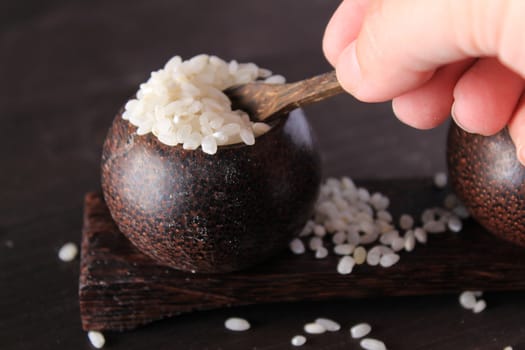 Small wooden bowls with white rice and hand holding a small spoon