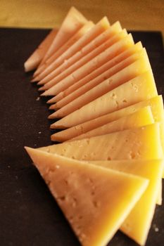 Manchego cheese slices in triangles on a black table