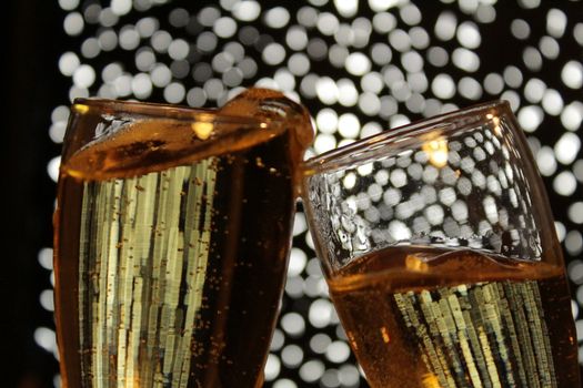 Champagne glasses toasting over Christmas light fantasy bokeh