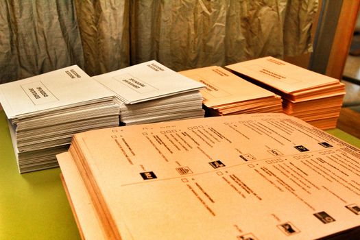 Ballots and envelops to vote on a wooden table at a polling station in Spain