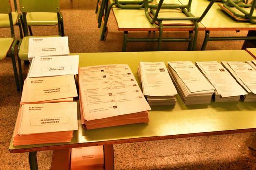 Ballots and envelops to vote on a wooden table at a polling station in Spain