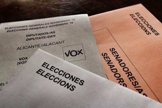Ballots and envelops to vote on a wooden table at a polling station in Spain