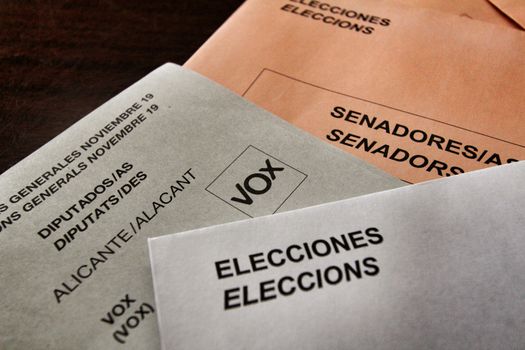 Ballots and envelops to vote on a wooden table at a polling station in Spain