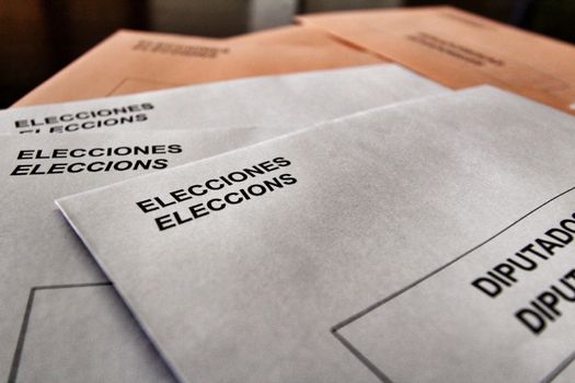 Ballots and envelops to vote on a wooden table at a polling station in Spain