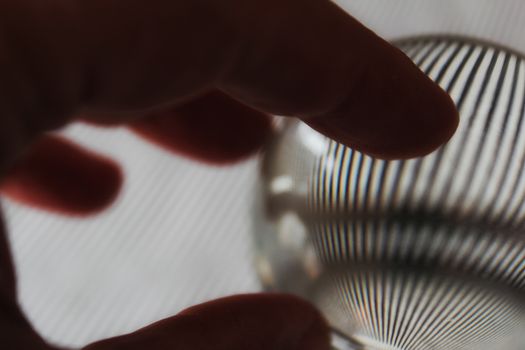 Hand on glass sphere with reflections